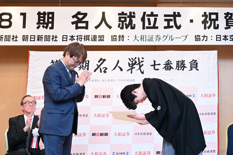 藤井名人に表彰状を渡してパチパチと拍手する羽生会長（写真は右に続きます）　©Keiji Ishikawa