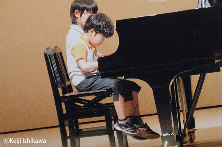 幼い頃の藤井聡太竜王がピアノを弾く姿　※写真を複写（写真は右に続きます）　©Keiji Ishikawa